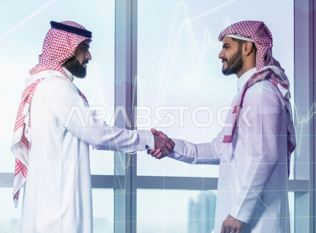 Two Saudi Arabian Gulf men shaking hands, business agreement, business deal, project and new business plan, business partners, progress and success, businessmen, Saudi work environment