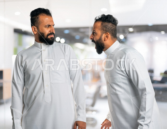 Two Gulf Arab-Saudi twins, a sharp discussion between two twin brothers, anger and blame, discussion and confrontation, asking and inquiring about something, irritability and tension, nervous pressure, gestures of the face and hands indicating anger.