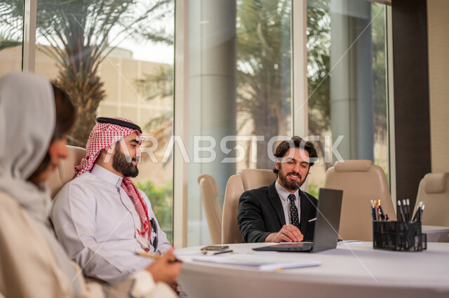 فريق عمل عربي خليجي سعودي في اجتماع عمل مع عميل جديد يرتدي البدلة الرسمية، استخدام الحاسوب المحمول في تطوير العمل وحل المشكلات، تطوير المشاريع، دراسة وتحليل المشاريع الجديدة، تقييم العمل الشراكي، الشراكة والتعاون، اجتماعات عمل، ورش عمل وتدريب