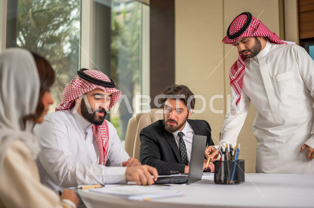 فريق عمل عربي خليجي سعودي في اجتماع عمل مع عميل جديد يرتدي البدلة الرسمية، استخدام الحاسوب المحمول في تطوير العمل وحل المشكلات، تطوير المشاريع، دراسة وتحليل المشاريع الجديدة، تقييم العمل الشراكي، الشراكة والتعاون، اجتماعات عمل، ورش عمل وتدريب