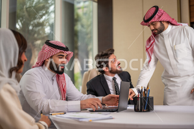 فريق عمل عربي خليجي سعودي في اجتماع عمل مع عميل جديد يرتدي البدلة الرسمية، استخدام الحاسوب المحمول في تطوير العمل وحل المشكلات، تطوير المشاريع، دراسة وتحليل المشاريع الجديدة، تقييم العمل الشراكي، الشراكة والتعاون، اجتماعات عمل، ورش عمل وتدريب