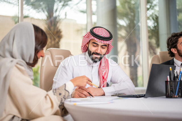فريق عمل عربي خليجي سعودي في اجتماع عمل مع عميل جديد يرتدي البدلة الرسمية، استخدام الحاسوب المحمول في تطوير العمل وحل المشكلات، تطوير المشاريع، دراسة وتحليل المشاريع الجديدة، تقييم العمل الشراكي، الشراكة والتعاون، اجتماعات عمل، ورش عمل وتدريب