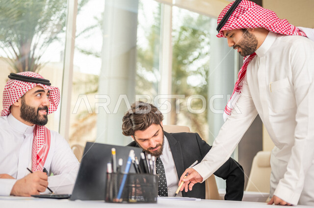 فريق عمل عربي خليجي سعودي في اجتماع عمل مع عميل جديد يرتدي البدلة الرسمية، استخدام الحاسوب المحمول في تطوير العمل وحل المشكلات، تطوير المشاريع، دراسة وتحليل المشاريع الجديدة، تقييم العمل الشراكي، الشراكة والتعاون، اجتماعات عمل، ورش عمل وتدريب