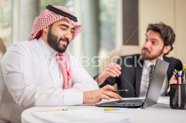فريق عمل عربي خليجي سعودي في اجتماع عمل مع عميل جديد يرتدي البدلة الرسمية، استخدام الحاسوب المحمول في تطوير العمل وحل المشكلات، تطوير المشاريع، دراسة وتحليل المشاريع الجديدة، تقييم العمل الشراكي، الشراكة والتعاون، اجتماعات عمل، ورش عمل وتدريب