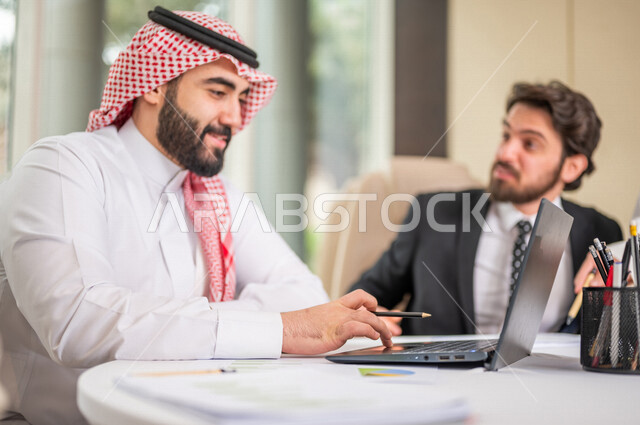 فريق عمل عربي خليجي سعودي في اجتماع عمل مع عميل جديد يرتدي البدلة الرسمية، استخدام الحاسوب المحمول في تطوير العمل وحل المشكلات، تطوير المشاريع، دراسة وتحليل المشاريع الجديدة، تقييم العمل الشراكي، الشراكة والتعاون، اجتماعات عمل، ورش عمل وتدريب