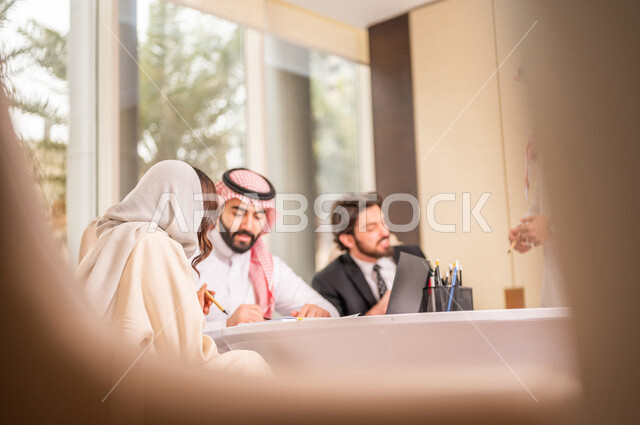 فريق عمل عربي خليجي سعودي في اجتماع عمل مع عميل جديد يرتدي البدلة الرسمية، استخدام الحاسوب المحمول في تطوير العمل وحل المشكلات، تطوير المشاريع، دراسة وتحليل المشاريع الجديدة، تقييم العمل الشراكي، الشراكة والتعاون، اجتماعات عمل، ورش عمل وتدريب