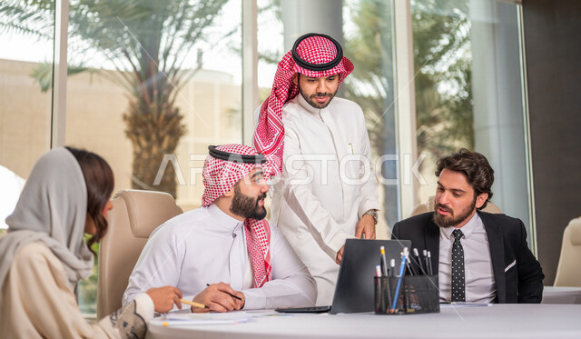 فريق عمل عربي خليجي سعودي في اجتماع عمل مع عميل جديد يرتدي البدلة الرسمية، استخدام الحاسوب المحمول في تطوير العمل وحل المشكلات، تطوير المشاريع، دراسة وتحليل المشاريع الجديدة، تقييم العمل الشراكي، الشراكة والتعاون، اجتماعات عمل، ورش عمل وتدريب