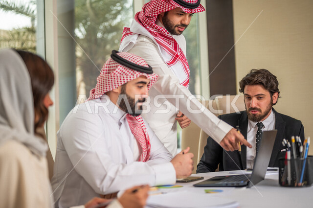 فريق عمل عربي خليجي سعودي في اجتماع عمل مع عميل جديد يرتدي البدلة الرسمية، استخدام الحاسوب المحمول في تطوير العمل وحل المشكلات، تطوير المشاريع، دراسة وتحليل المشاريع الجديدة، تقييم العمل الشراكي، الشراكة والتعاون، اجتماعات عمل، ورش عمل وتدريب
