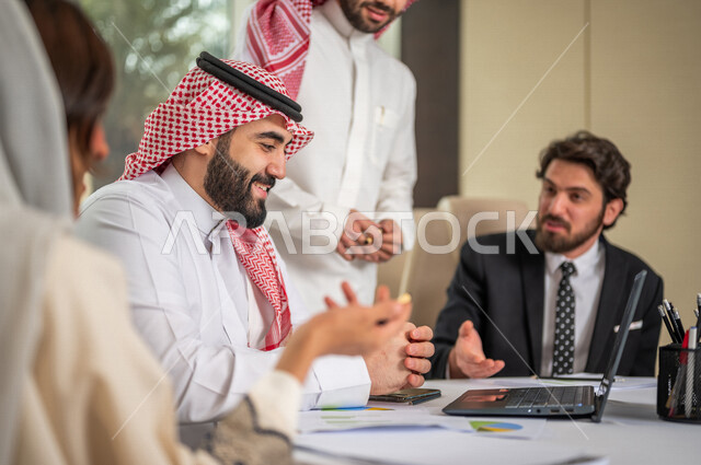 فريق عمل عربي خليجي سعودي في اجتماع عمل مع عميل جديد يرتدي البدلة الرسمية، استخدام الحاسوب المحمول في تطوير العمل وحل المشكلات، تطوير المشاريع، دراسة وتحليل المشاريع الجديدة، تقييم العمل الشراكي، الشراكة والتعاون، اجتماعات عمل، ورش عمل وتدريب