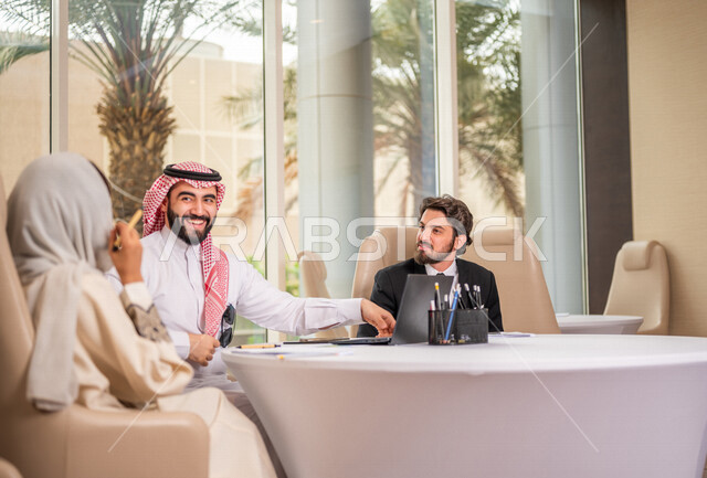 فريق عمل عربي خليجي سعودي في اجتماع عمل مع عميل جديد يرتدي البدلة الرسمية، استخدام الحاسوب المحمول في تطوير العمل وحل المشكلات، تطوير المشاريع، دراسة وتحليل المشاريع الجديدة، تقييم العمل الشراكي، الشراكة والتعاون، اجتماعات عمل، ورش عمل وتدريب