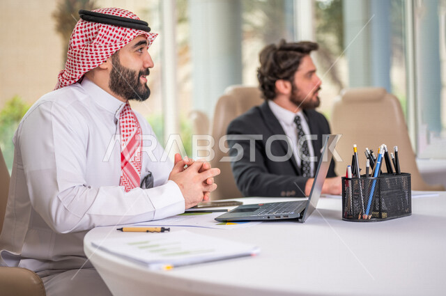 فريق عمل عربي خليجي سعودي في اجتماع عمل مع عميل جديد يرتدي البدلة الرسمية، استخدام الحاسوب المحمول في تطوير العمل وحل المشكلات، تطوير المشاريع، دراسة وتحليل المشاريع الجديدة، تقييم العمل الشراكي، الشراكة والتعاون، اجتماعات عمل، ورش عمل وتدريب