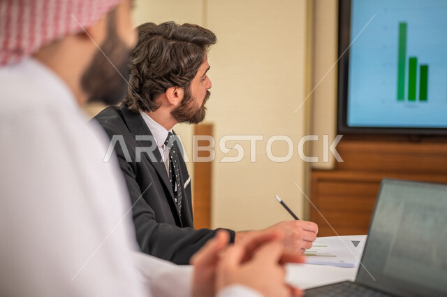 فريق عمل عربي خليجي سعودي في اجتماع عمل مع عميل جديد يرتدي البدلة الرسمية، تطوير المشاريع، دراسة وتحليل المشاريع الجديدة، تقييم العمل الشراكي، الشراكة والتعاون، اجتماعات عمل، ورش عمل وتدريب