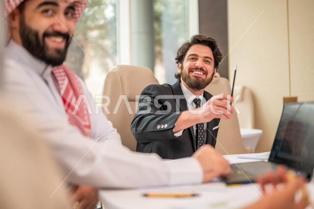 فريق عمل عربي خليجي سعودي في اجتماع عمل مع عميل جديد يرتدي البدلة الرسمية، استخدام الحاسوب المحمول في تطوير العمل وحل المشكلات، تطوير المشاريع، دراسة وتحليل المشاريع الجديدة، تقييم العمل الشراكي، الشراكة والتعاون، اجتماعات عمل، ورش عمل وتدريب