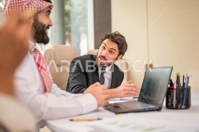 فريق عمل عربي خليجي سعودي في اجتماع عمل مع عميل جديد يرتدي البدلة الرسمية، استخدام الحاسوب المحمول في تطوير العمل وحل المشكلات، تطوير المشاريع، دراسة وتحليل المشاريع الجديدة، تقييم العمل الشراكي، الشراكة والتعاون، اجتماعات عمل، ورش عمل وتدريب