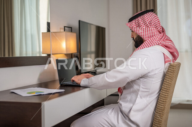 رجل عربي خليجي سعودي يقوم بتحليل البيانات على الحاسوب المحمول، متابعة مخطط الرسم البياني، تدقيق وتحليل بيانات المشروع، دراسة مشاريع جديدة، صعود وهبوط البورصة، النمو الاقتصادي، الاستثمار المالي