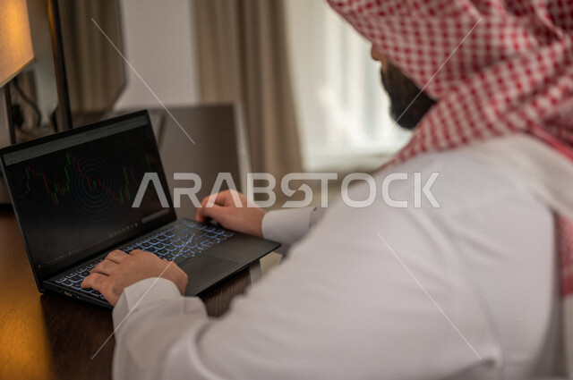 رجل عربي خليجي سعودي يقوم بتحليل البيانات على الحاسوب المحمول، متابعة مخطط الرسم البياني، تدقيق وتحليل بيانات المشروع، دراسة مشاريع جديدة، صعود وهبوط البورصة، النمو الاقتصادي، الاستثمار المالي