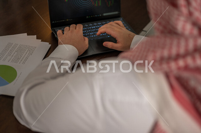رجل عربي خليجي سعودي يقوم بتحليل البيانات على الحاسوب المحمول، متابعة مخطط الرسم البياني، تدقيق وتحليل بيانات المشروع، دراسة مشاريع جديدة، صعود وهبوط البورصة، النمو الاقتصادي، الاستثمار المالي