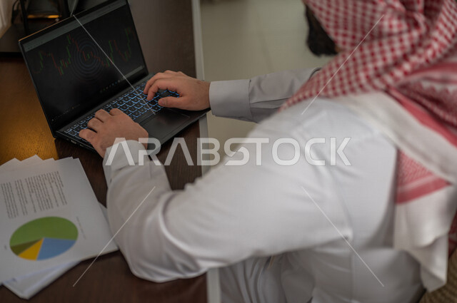 رجل عربي خليجي سعودي يقوم بتحليل البيانات على الحاسوب المحمول، متابعة مخطط الرسم البياني، تدقيق وتحليل بيانات المشروع، دراسة مشاريع جديدة، صعود وهبوط البورصة، النمو الاقتصادي، الاستثمار المالي