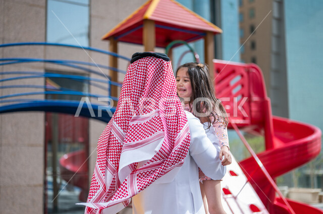 رجل عربي خليجي سعودي مستمتع بقضاء وقت ممتع مع ابنته في احدا الحدائق في المملكة العربية السعودية  ، التسلية والترفيه ، اجواء صيفية ممتعة ، قضاء وقت عائلي ممتع، عطلة صيفية سعيدة