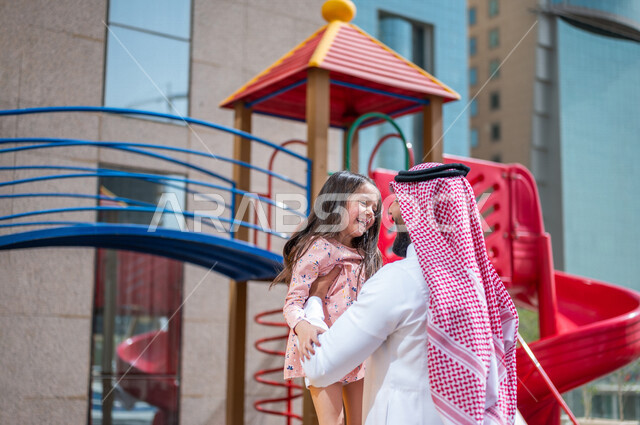 رجل عربي خليجي سعودي مستمتع باللعب مع ابنته في احد المتنزهات الترفيهية ، التسلية والترفيه ، اجواء صيفية ممتعة ، رحلة سياحية ترفيهية ، عطلة صيفية سعيدة