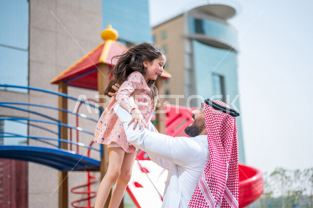 رجل عربي خليجي سعودي مستمتع بقضاء وقت ممتع مع ابنته في احدا الحدائق في المملكة العربية السعودية  ، التسلية والترفيه ، اجواء صيفية ممتعة ، قضاء وقت عائلي ممتع، عطلة صيفية سعيدة