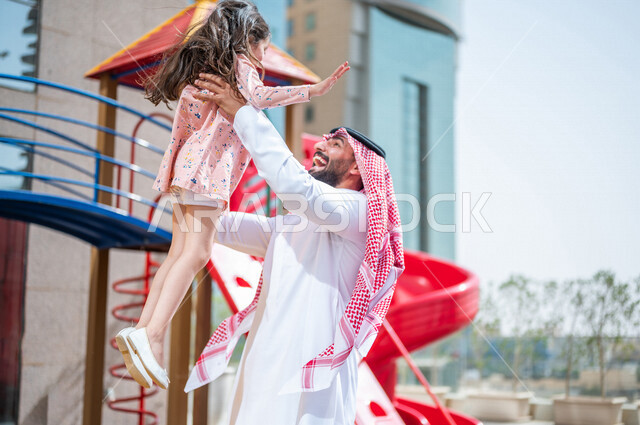 رجل عربي خليجي سعودي مستمتع بقضاء وقت ممتع مع ابنته في احدا الحدائق في المملكة العربية السعودية  ، التسلية والترفيه ، اجواء صيفية ممتعة ، قضاء وقت عائلي ممتع، عطلة صيفية سعيدة