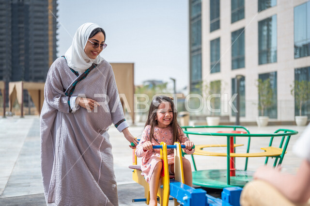 A Saudi Arabian Gulf woman spends her time with her children, children's participation in recreational activities, summer recreational activities, playing with recreational games, spending fun family time, happy summer vacation