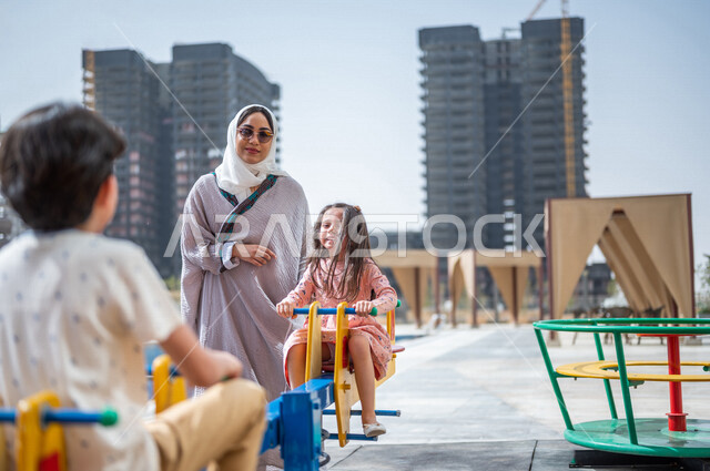 A Saudi Arabian Gulf woman spends her time with her children, children's participation in recreational activities, summer recreational activities, playing with recreational games, spending fun family time, happy summer vacation