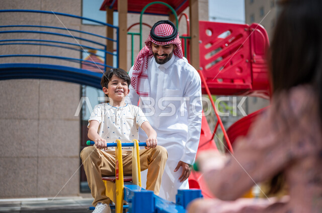 رجل عربي خليجي سعودي يقضي وقت ممتع مع ابنه  ، الاستمتاع باللعب بالالعاب الترفيهية  ، التسلية والترفيه ،مشاركة الاطفال بالانشطة الترفيهية ، انشطة صيفية ترفيهية ، قضاء وقت عائلي ممتع، عطلة صيفية سعيدة 
