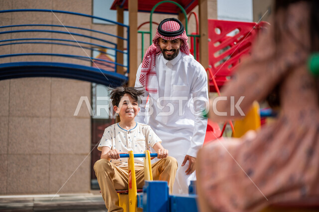 رجل عربي خليجي سعودي يقضي وقت ممتع مع ابنه  ، الاستمتاع باللعب بالالعاب الترفيهية  ، التسلية والترفيه ،مشاركة الاطفال بالانشطة الترفيهية ، انشطة صيفية ترفيهية ، قضاء وقت عائلي ممتع، عطلة صيفية سعيدة 