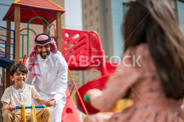 رجل عربي خليجي سعودي يقضي وقت ممتع مع ابنه  ، الاستمتاع باللعب بالالعاب الترفيهية  ، التسلية والترفيه ،مشاركة الاطفال بالانشطة الترفيهية ، انشطة صيفية ترفيهية ، قضاء وقت عائلي ممتع، عطلة صيفية سعيدة 