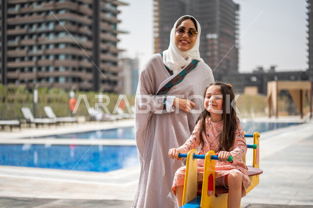 A Saudi Arabian Gulf woman spending quality time with her daughter, children participating in recreational activities, summer recreational activities, playing with recreational games, spending fun family time, happy summer vacation