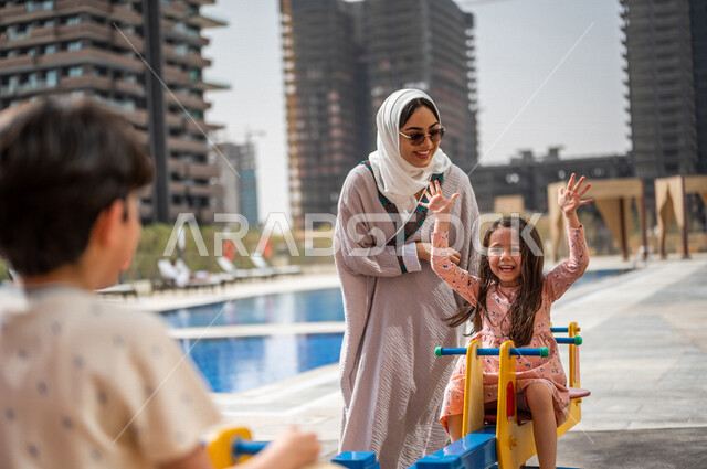 A Saudi Arabian Gulf woman spends her time with her children, children's participation in recreational activities, summer recreational activities, playing with recreational games, spending fun family time, happy summer vacation
