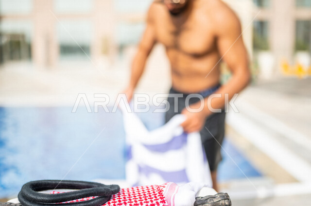 رجل عربي خليجي سعودي يستخدم المنشفة بعد الانتهاء من السباحة ، حمام سباحة ، شاليهات ومنتجعات، انشطة ترفيهية مائية ، عطلة صيفية سعيدة 