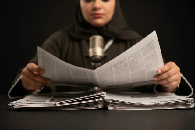 Saudi Female Journalist Reading Newspaper in Studio