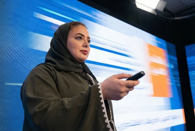 امرأة سعودية تقدم عرضا أمام شاشة رقمية