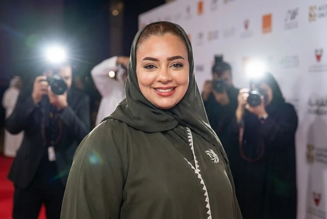 امرأة سعودية بالعباءة الخضراء على السجادة الحمراء