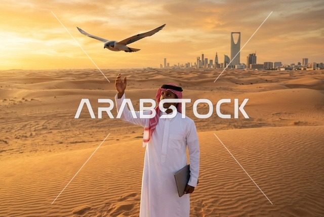 رجل سعودي مع صقر ولابتوب في صحراء الرياض وقت الغروب