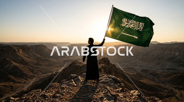 مواطن سعودي يحمل العلم الوطني فوق الكثبان الرملية