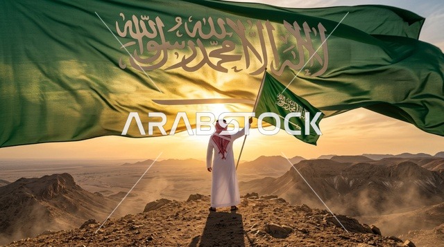 مواطن سعودي يحمل العلم الوطني فوق الكثبان الرملية