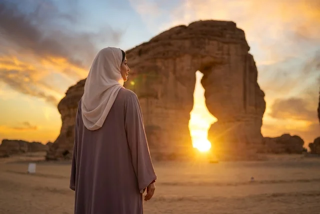 امرأة سعودية تقف عند صخرة الفيل في العلا وقت الغروب