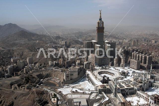منظر لمدينة يتميز بناطحة سحاب بارزة ذات قبة ذهبية، محاطة بمبانٍ حديثة وتضاريس صحراوية.