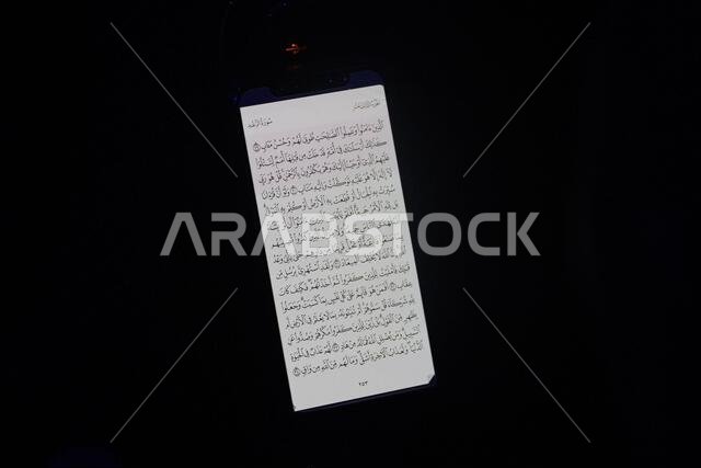 تتألق صفحة الكتاب البيضاء ذات الخط العربي الكثيف على خلفية داكنة.