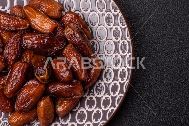 Dried dates on a ceramic plate for Ramadan or Iftar. Dried dates as a food background for your design
