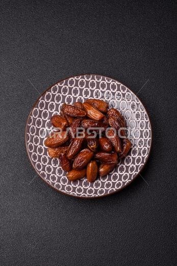 Dried dates on a ceramic plate for Ramadan or Iftar. Dried dates as a food background for your design