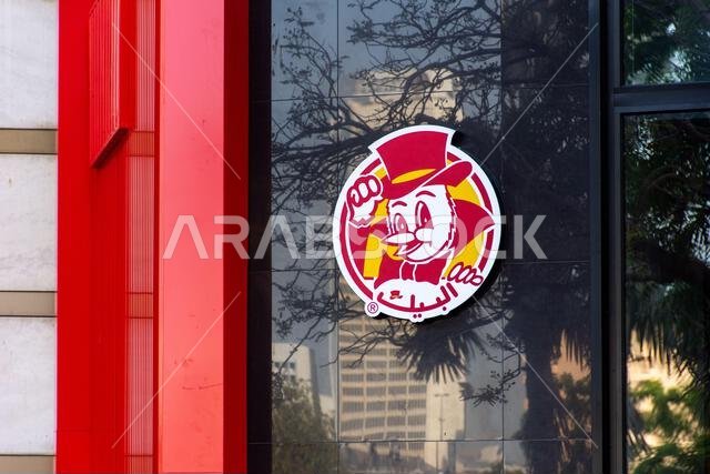 شعار مطعم البيك للوجبات السريعة الدائري على واجهة مبنى عاكسة.