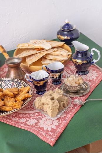 حلويات شرقية وأكواب قهوة على الطاولة. بقلاوة وحلوى حلاوة طحينية للتحلية. طعام وشراب.