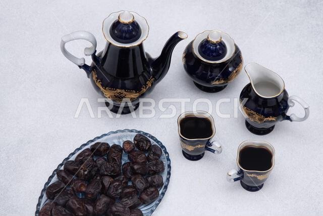 طقم قهوة يتضمن إبريقًا، وإبريقًا للكريمة، ووعاءً أزرق للسكر، وأكوابًا. أدوات مائدة عتيقة. تمر حلو. مشروب طقم قهوة يتضمن إبريقًا، وإبريقًا للكريمة، ووعاءً أزرق للسكر، وأكوابًا. أدوات مائدة عتيقة. تمر حلو. مشروب