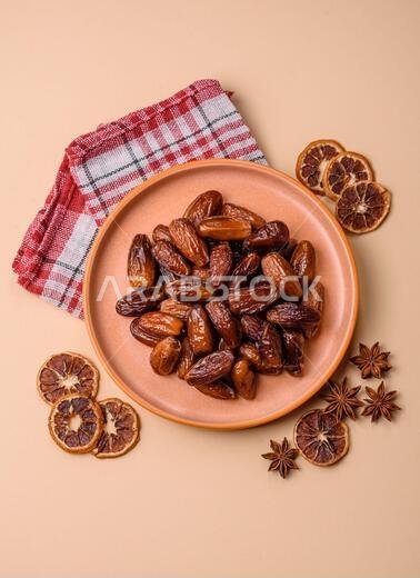 Dried dates on a ceramic plate for Ramadan or Iftar. Dried dates as a food background for your design Dried dates on a ceramic plate for Ramadan or Iftar. Dried dates as a food background for your design