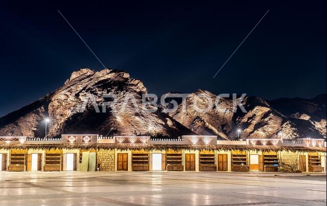 Traditional marketplace buildings at the base of Mount Uhud illuminated at night in Medina, Saudi Arabia.